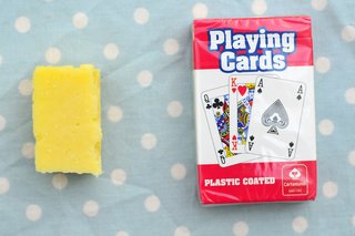 A matchbox-sized piece of cheddar cheese next to a pack of cards