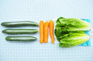 3 cucumbers, 3 carrots and 2 heads of lettuce on a table