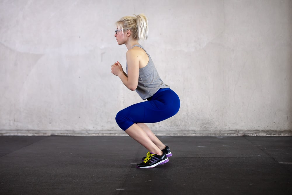 woman lifting heels of the floor while doing a squat