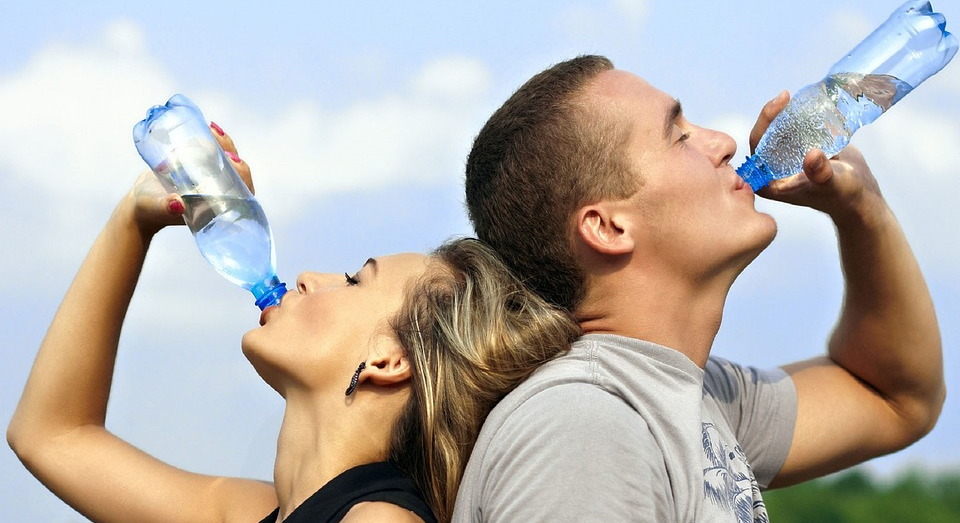 Мужчина и женщина пьют воду из бутылок