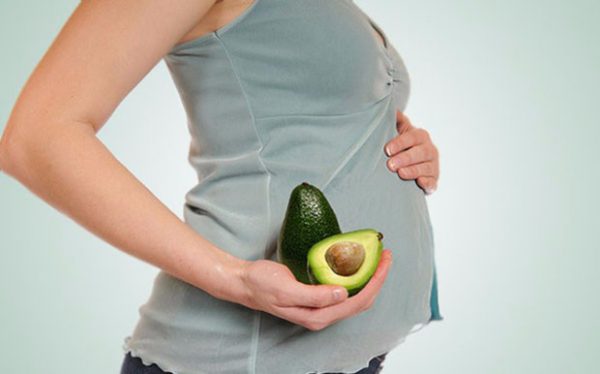 Беременная женщина держит авокадо